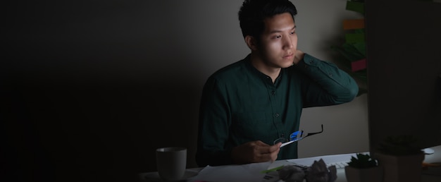 Photo séduisante jeune homme asiatique travaillant tard dans la nuit à la recherche d'un ordinateur portable