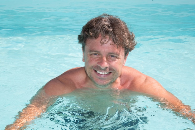 Séduisante jeune homme dans le fond bleu de la piscine