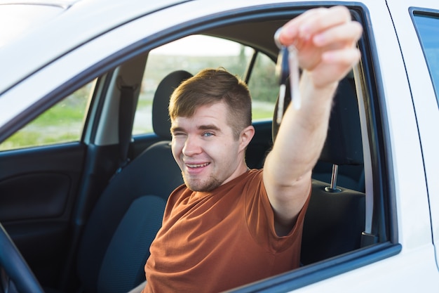 Séduisante jeune homme heureux montrant ses nouvelles clés de voiture et riant.