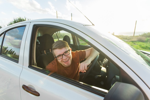 Séduisante jeune homme heureux montrant ses nouvelles clés de voiture et riant.