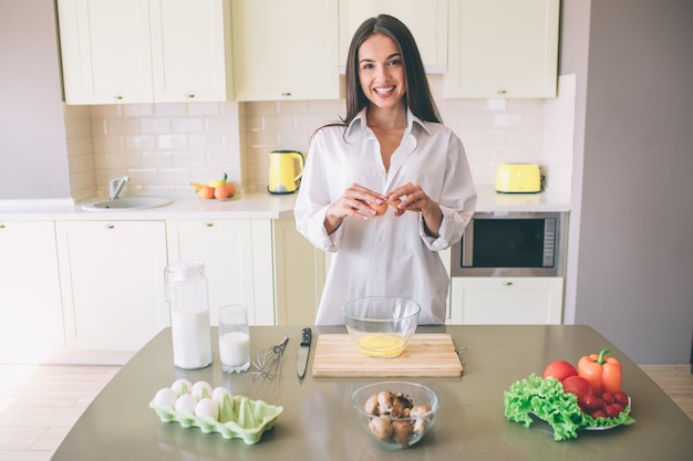 Séduisante et magnifique jeune femme se tient à la table dans la cuisine