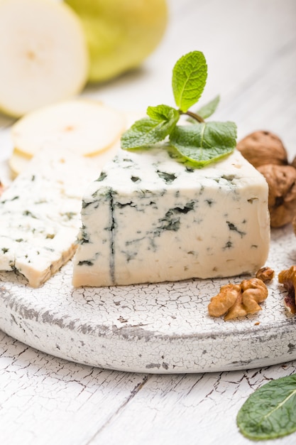 Segment de fromage moule bleu - Gorgonzola avec poire et noix sur planche de bois.