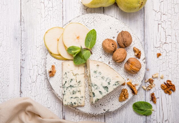 Segment de fromage moule bleu - Gorgonzola avec poire et noix sur planche de bois.