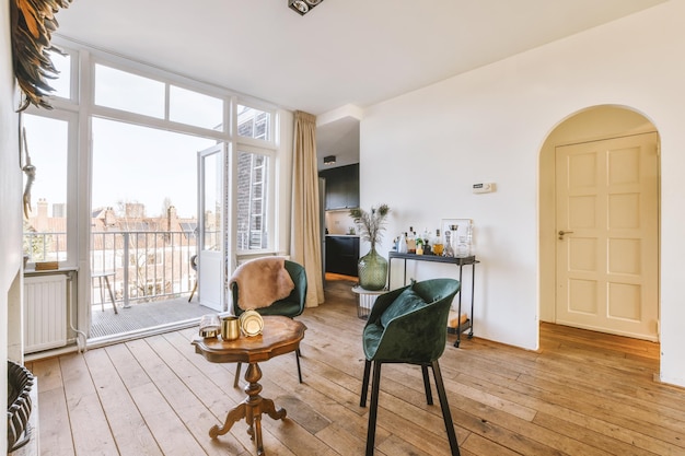 Séjour avec chaises et petite table en bois balcon porte-boissons et passage vers la cuisine