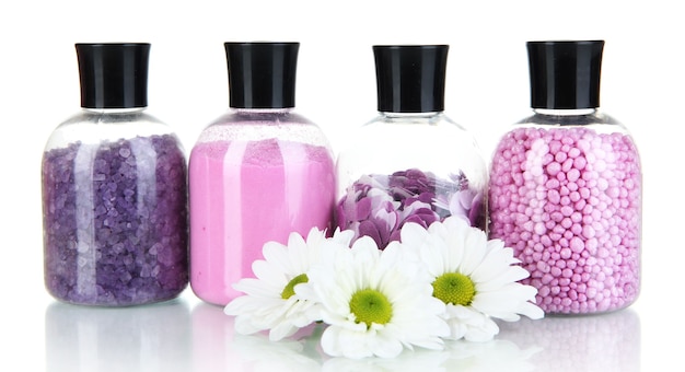 Sel de bain coloré dans des bouteilles et des fleurs sur une surface claire