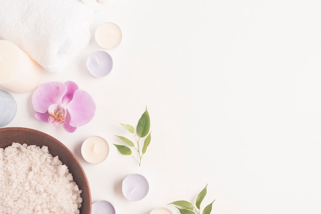 Photo sel de bain avec fleur d'orchidée et bougies sur fond blanc