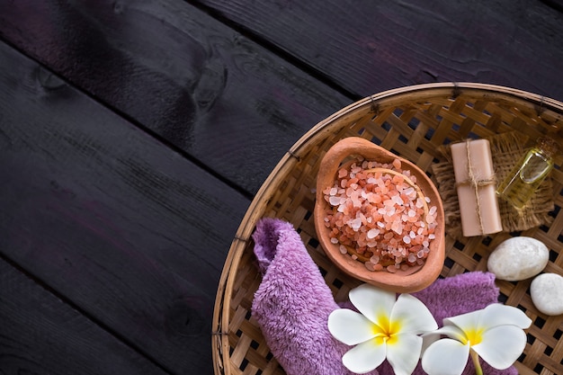 Sel de l'Himalaya avec des fleurs de frangipanier et du savon, une serviette dans un panier en osier sur fond de bois. concept de spa d'aromathérapie. pour hôtel spa de luxe.