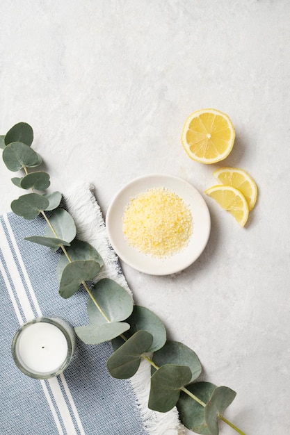 Sel de mer jaune bio avec bougie au citron et branche d'eucalyptus sur fond blanc texturé Le concept de spa et de bien-être Vue de dessus et espace de copie