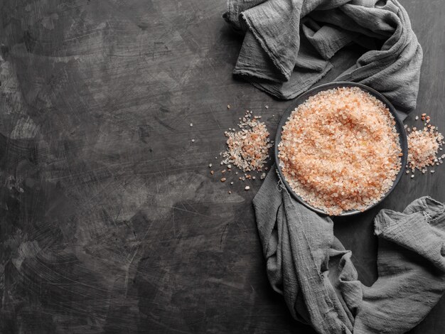 Sel rose de l'Himalaya dans une assiette sur une table avec un chiffon gris. Vue de dessus.