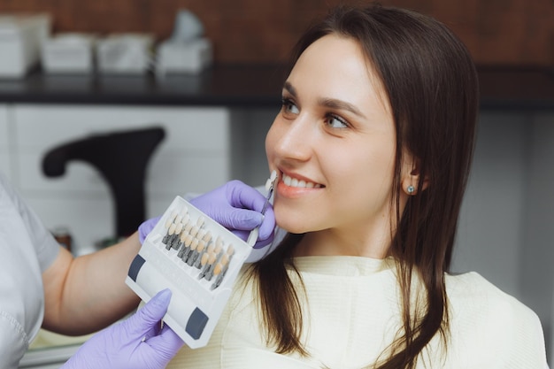 Sélection de la bonne couleur de dent pour le blanchiment cosmétique professionnel chez le dentiste le médecin sélectionne les dents pour le patient