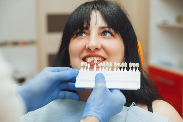 Sélection de la bonne couleur de dent pour le blanchiment cosmétique professionnel chez le dentiste le médecin sélectionne les dents pour le patient