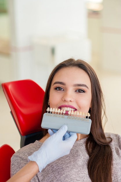 Sélection de la couleur des dents pour une belle fille en dentisterie.