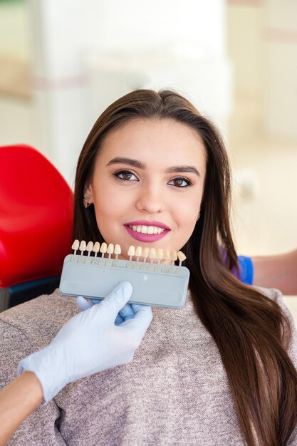 Sélection de la couleur des dents pour une belle fille en dentisterie.