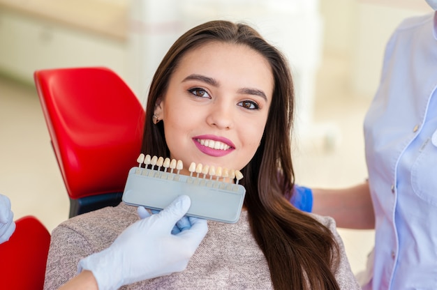 Sélection de la couleur des dents pour une belle fille en dentisterie.