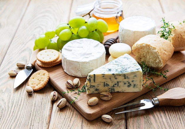 Sélection de fromages, miel et raisin sur fond de béton gris