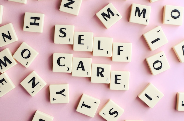 SELF CARE - texte sur des cubes en bois sur fond rose