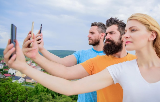 Selfie apporté par la confiance en soi Jolie femme et hommes tenant des smartphones dans les mains Meilleurs amis prenant un selfie avec un téléphone appareil photo Personnes prenant un selfie sur la nature Partageant un selfie sur un réseau social