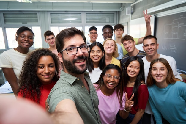 Selfie joyeux d'un jeune groupe d'étudiants Erasmus prenant une photo avec leur professeur en classe
