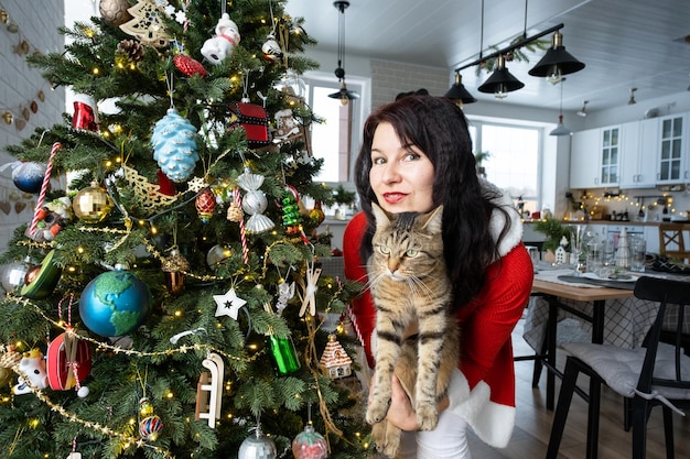 Selfie portrait drôle d'une femme dans une robe de Père Noël rouge et un chat domestique