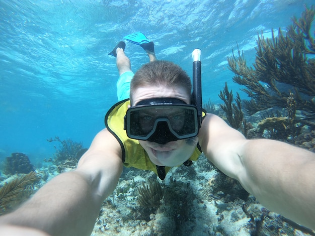 Selfie sous-marin grand angle du nageur dans une eau cristalline avec la vie de la marina. avec gilet de sauvetage