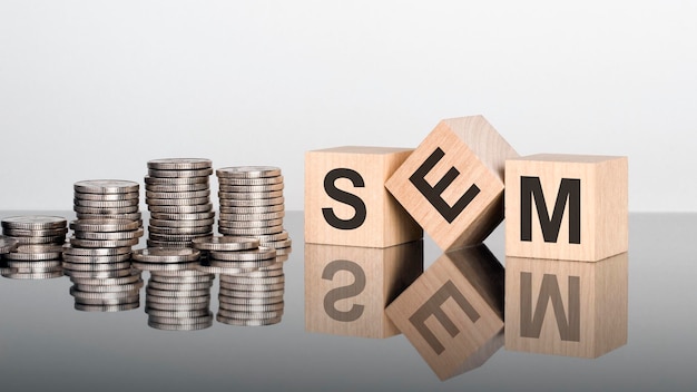 SEM le texte est composé de lettres sur des cubes en bois posés sur une surface miroir