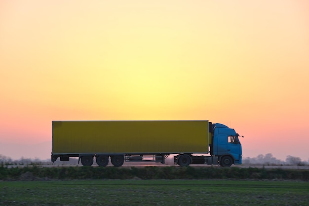 Semi-camion avec remorque cargo roulant sur autoroute transportant des marchandises en soirée. Concept de transport et de logistique de livraison.