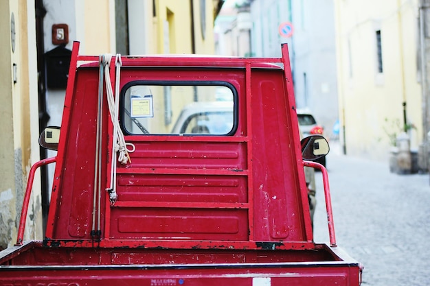 Un semi-camion rouge sur la route contre des bâtiments.