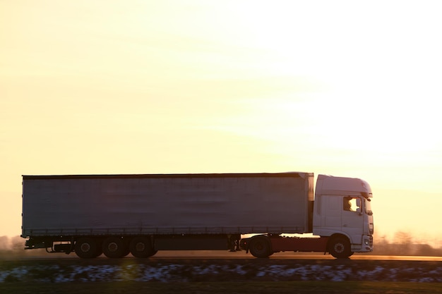 Semi-remorque avec remorque de fret roulant sur l'autoroute transportant des marchandises en soirée Concept de transport et de logistique de livraison