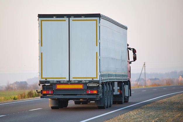 Semi-remorque avec remorque de fret roulant sur l'autoroute transportant des marchandises en soirée Concept de transport et de logistique de livraison