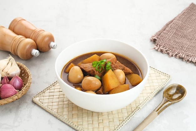 Semur, cuisine traditionnelle indonésienne, avec du tofu, des œufs de caille et des pommes de terre, servi dans un bol.