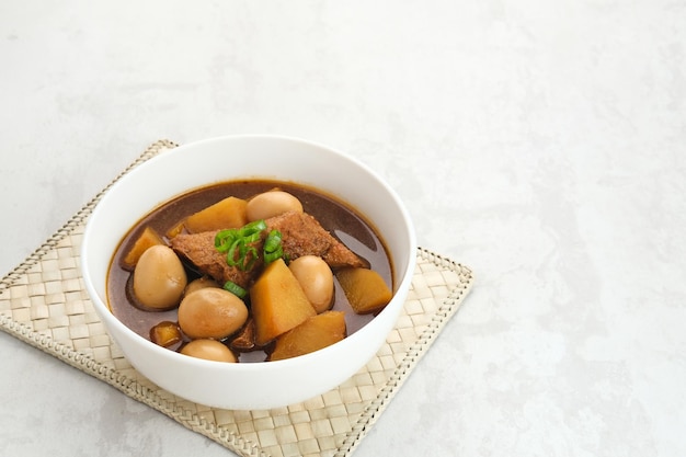 Semur, cuisine traditionnelle indonésienne, avec du tofu, des œufs de caille et des pommes de terre, servi dans un bol.