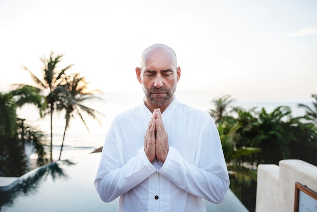 Senior adulte pratiquant le yoga au bord de la piscine