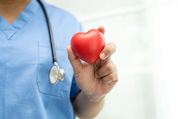 Senior asiatique ou vieille dame âgée patiente tenant un coeur rouge dans sa main sur le lit dans l'hôpital de soins infirmiers sain concept médical fort