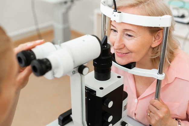Senior beau femme visitant l'ophtalmologiste et vérifiant sa vue