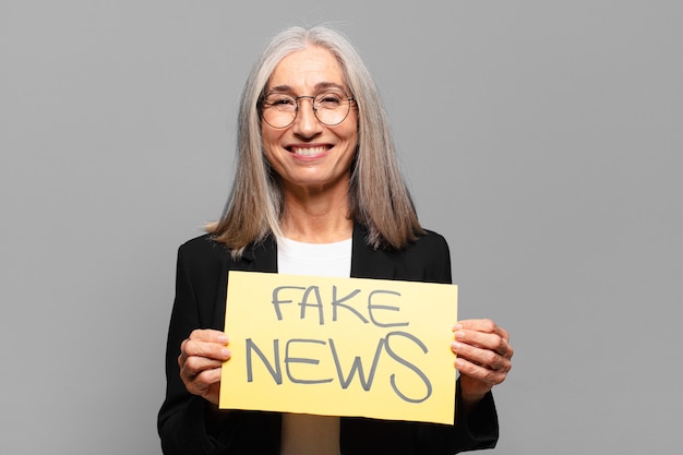 Senior businesswoman with fake news sign