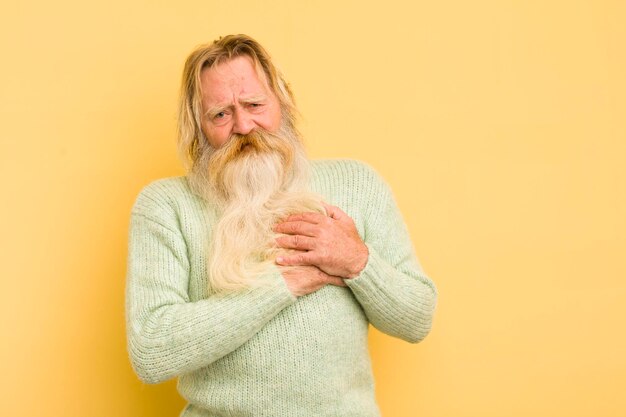 Senior cool barbu à la triste blessure et le cœur brisé tenant les deux mains près du cœur pleurant et se sentant déprimé