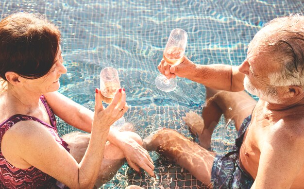 Senior couple buvant du prosecco dans une piscine