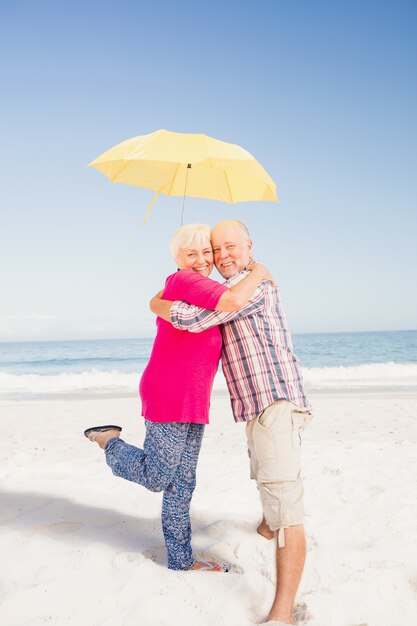 Senior couple embrassant et tenant un parapluie