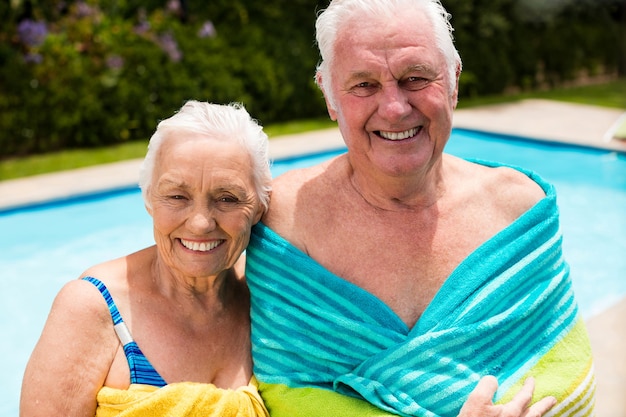 Senior couple enveloppé dans une serviette au bord de la piscine
