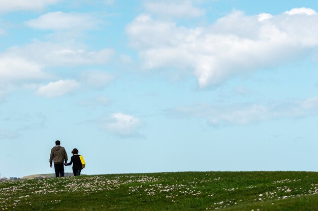 Senior Couple Marchant Joyeusement Dans Le Parc Avec Un Ciel Bleu En Arrière-plan.