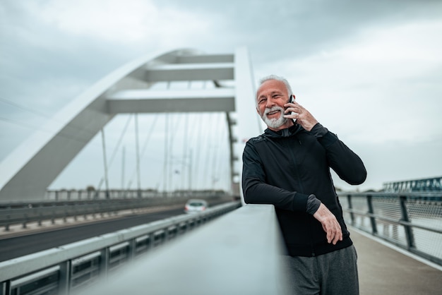 Senior coureur actif parlant au téléphone.