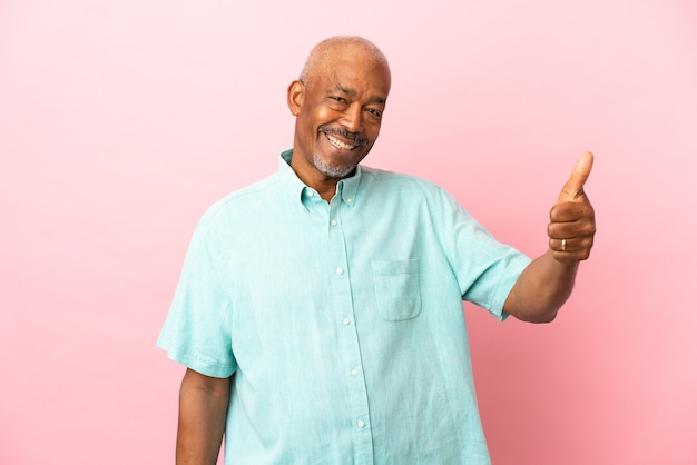 Senior cubain isolé sur fond rose avec le pouce levé parce que quelque chose de bien s'est produit