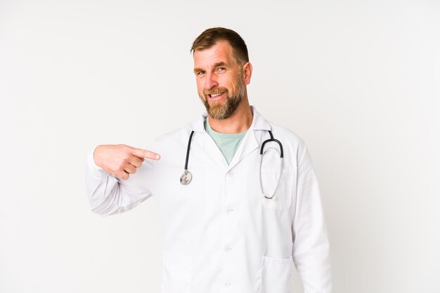 Senior doctor man isolated on white wall personne pointant à la main vers un espace de copie de chemise, fier et confiant