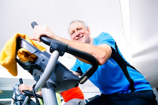 Senior Faire Du Sport Sur Spinning Bike In Gym