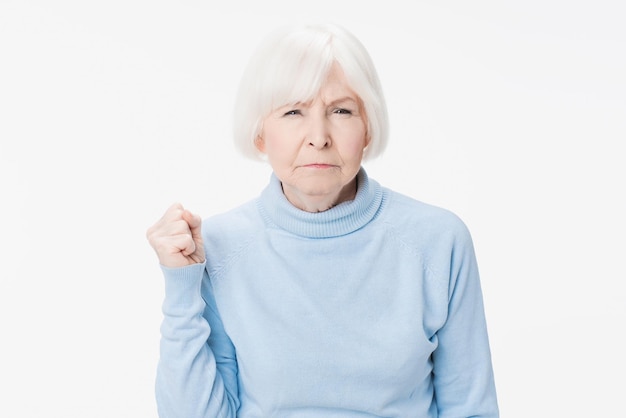 Senior femme aux cheveux gris en colère sur fond blanc isolé