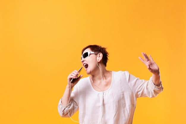 Senior femme chantant et écoutant de la musique