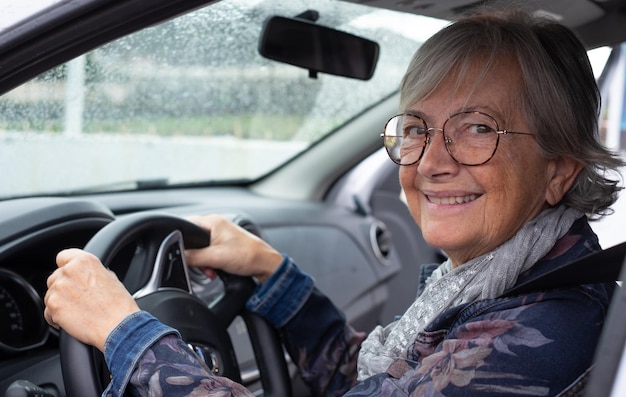 Senior femme conducteur conduisant sa voiture un jour de pluie