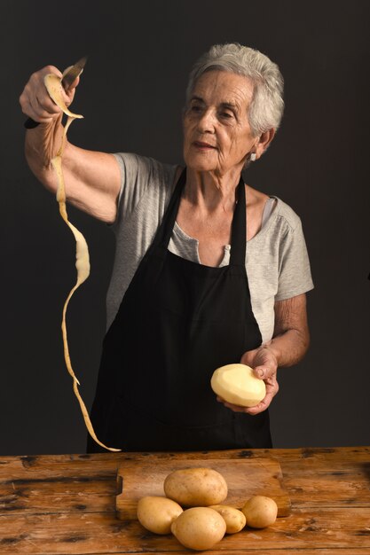 Senior femme éplucher des pommes de terre