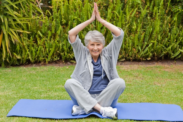 Senior femme fait ses étirements dans le jardin