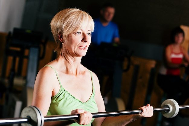 Senior femme avec haltères en gym